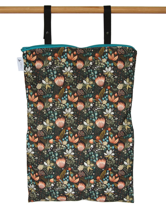 Floral-patterned reusable wet bag hanging on a wooden rod against a white background