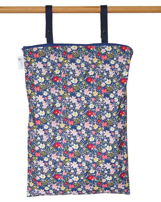 Floral-patterned reusable wet bag hanging on a wooden rod against a white background
