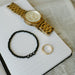flatlay of dad beaded bracelet next to watch, ring and notebook on top of a newspaper