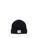 A black ribbed knit beanie hat with a white rectangular brand patch on the front cuff, photographed against a white background.