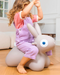 Child sitting on a gray inflatable bunny toy indoors.