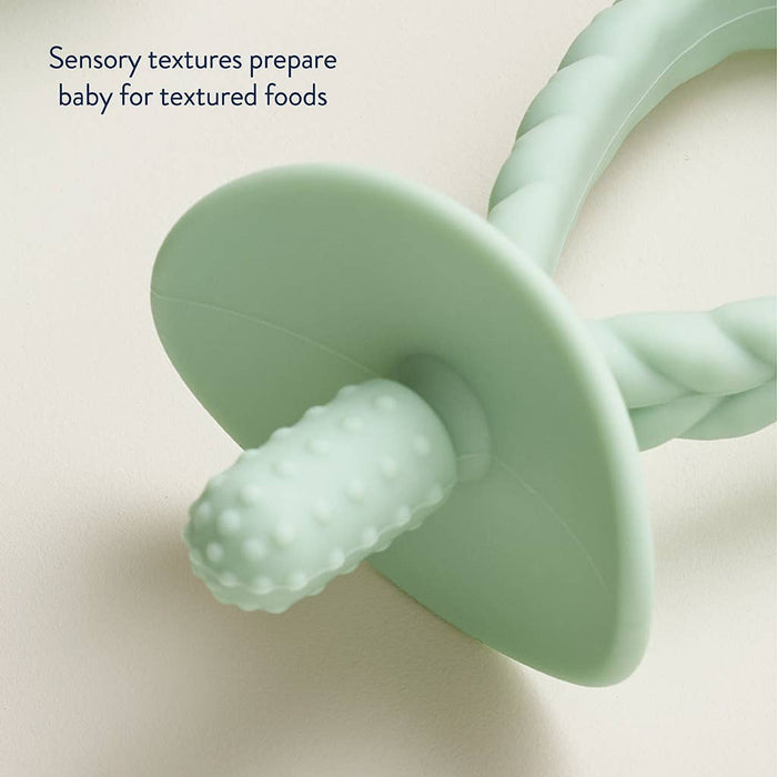 Green baby teether with textured design on a light beige background