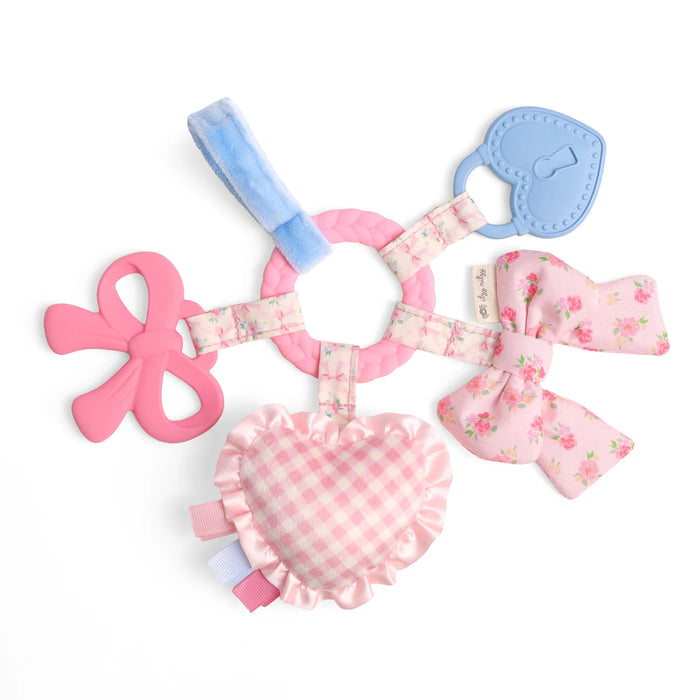 Pink and blue baby teething ring with bow designs on a white background
