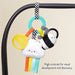 Colorful baby toy with cloud design hanging from a crib bar on a beige background.