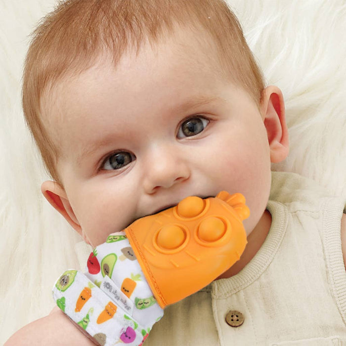 Baby holding an orange teething toy with a colorful handle