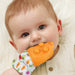 Baby holding an orange teething toy with a colorful handle