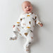 Baby wearing a white onesie with animal prints on a plain background