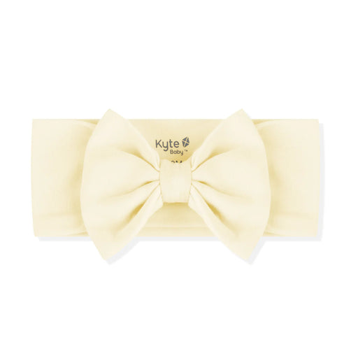 Cream-colored headband with a large bow on a white background, branded 'Kyte Baby'.