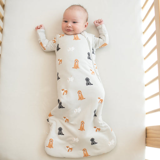 Baby lying in a crib wearing a sleepsack with a dog pattern in a crib