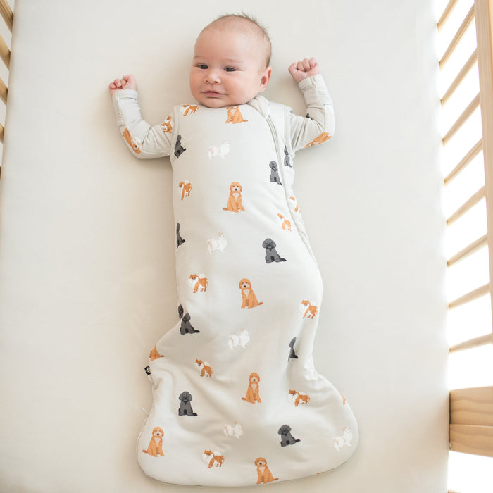 Baby lying in a crib wearing a sleepsack with a dog pattern in a crib