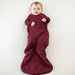 Child zipped into a burgundy 1.0 bamboo sleep sack on a white background