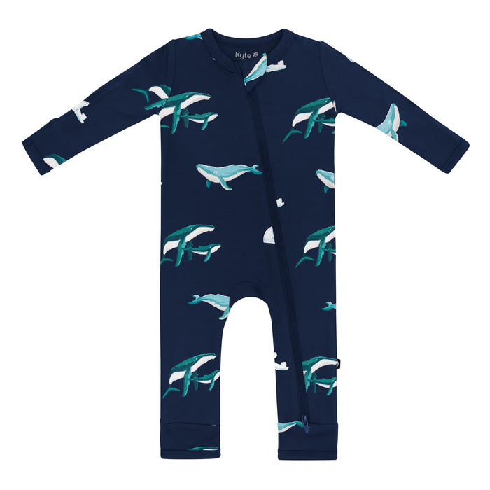 Navy blue baby long sleeved romper onesie with humpback whale pattern against a white background