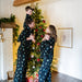 Family in matching Kyte pajamas standing in front of a decorated Christmas tree.