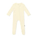 Cream-colored baby onesie with feet on a white background