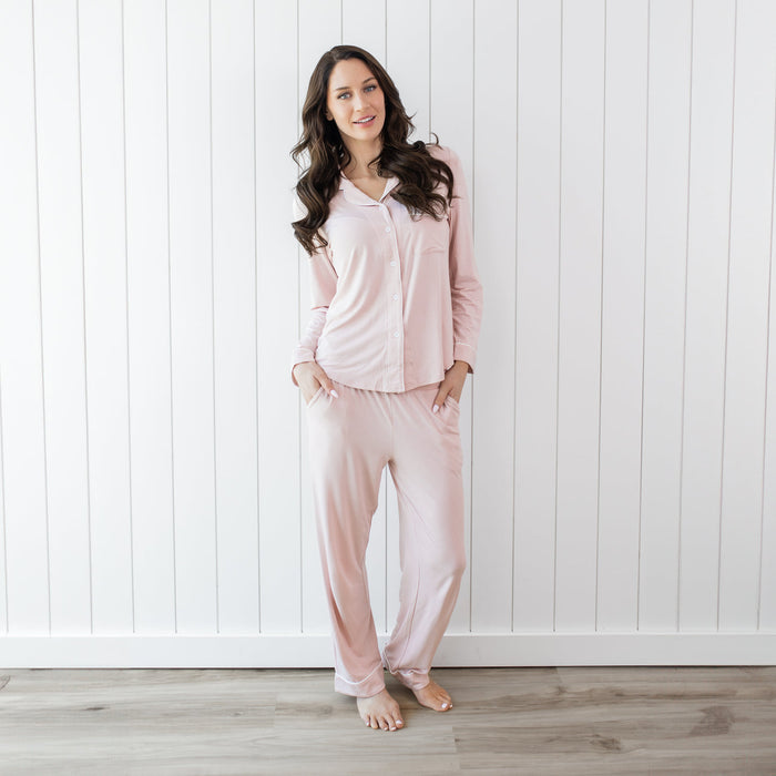 Woman wearing pink pajamas standing against a white wooden panel background