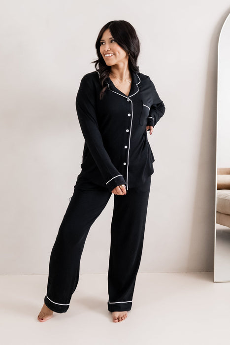 Woman wearing black pajamas with white buttons in a minimalistic setting