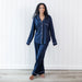 Woman wearing a navy blue pajama set against a white wooden panel background