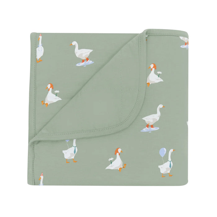 Folded green blanket with goose pattern on a white background