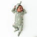 Newborn baby wearing a green outfit with goose print on a white background