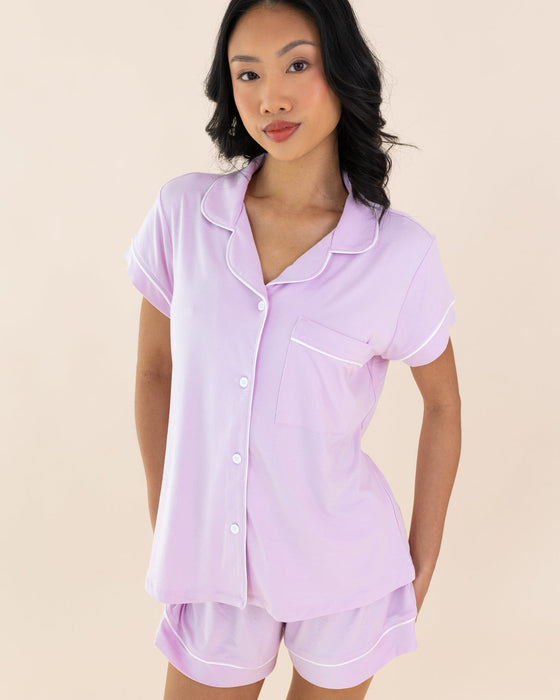 Woman wearing a light purple pajama set against a beige background