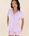 Woman wearing a light purple pajama set against a beige background