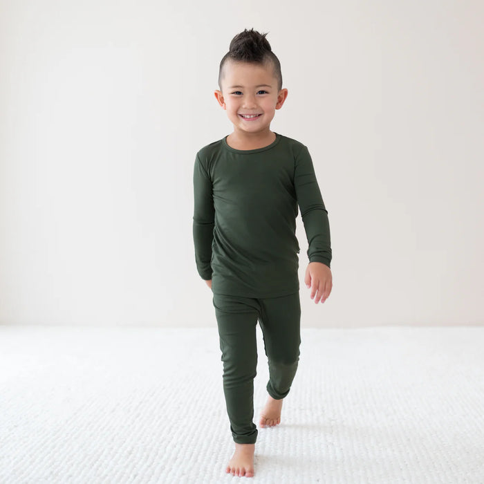 Child wearing a green long-sleeve pj shirt and pants on a white background