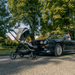 Black stroller next to a black BMW car on a tree-lined street