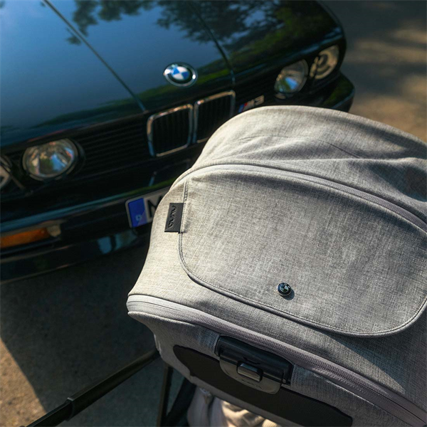 Gray stroller with a BMW car in the background