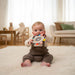 Baby sitting on a rug in a living room holding a toy