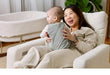 Woman sitting in a monte chair holding a baby in a home setting