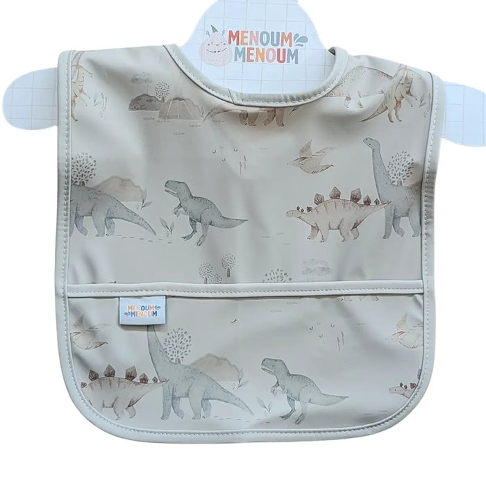 A baby bib with a dinosaur print, featuring a front pouch pocket shown on a white background with a Menoum Menoum brand label.