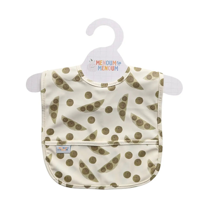 a sleeveless baby bib with green peas on a beige fabric set on a hanger on a white background