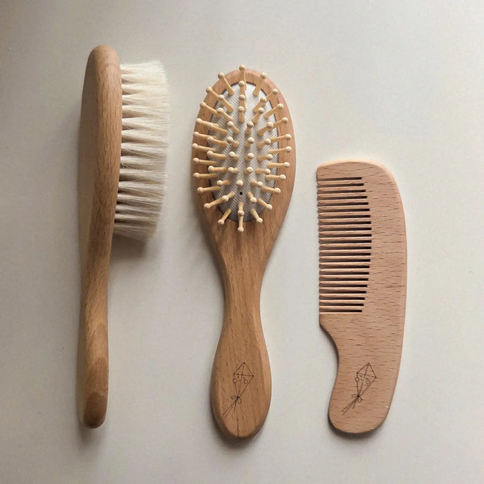Three wooden hair brush and comb tools arranged vertically on a light neutral background