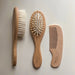 Three wooden hair brush and comb tools arranged vertically on a light neutral background