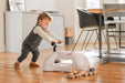 Child playing with a my first ride on, on a wooden floor in a home setting.