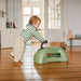 Child playing with a scoot and ride on a wooden floor in a home setting