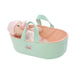 Baby doll in a mint green and pink bassinet with 'Love, Stella' branding.