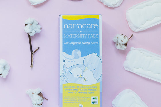 Natracare maternity pads packaging on a pink background with cotton elements