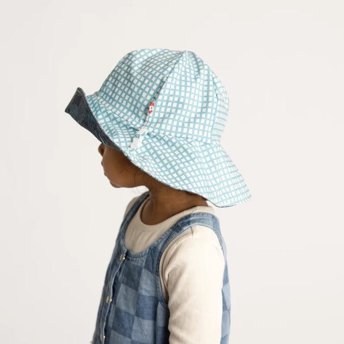 Child wearing a blue checkered hat on a light gray background