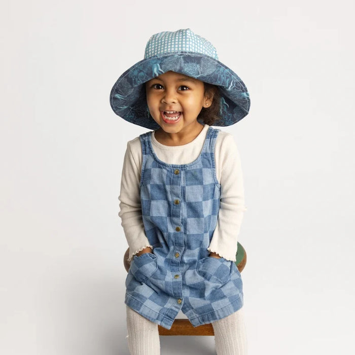 Child wearing a reversible checkered sun hat on a white background