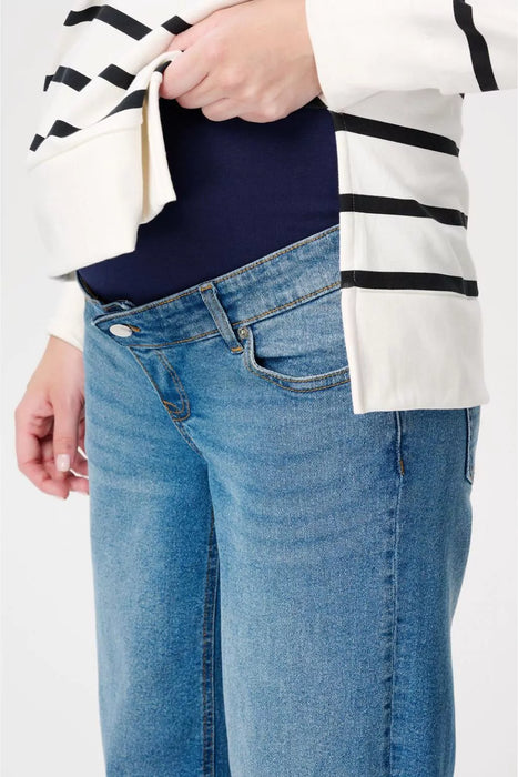 Person wearing a white and black striped sweater over a navy shirt with blue jeans on a white background