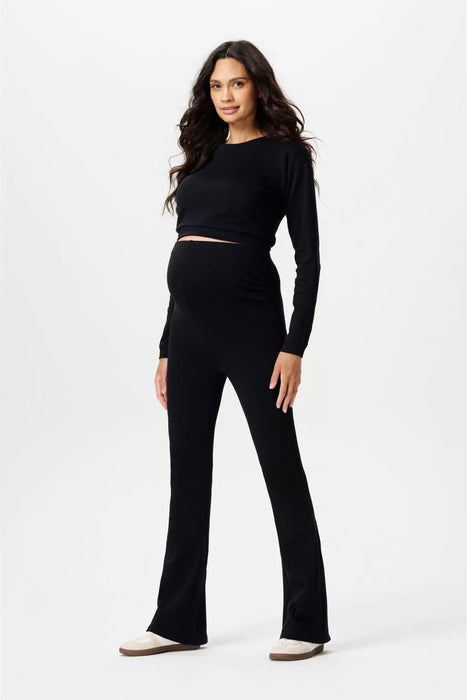 Woman wearing a black long-sleeve top and black flared maternity pants on a white background