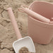 Pink sand bucket and shovel on a sandy surface with 'nouka' branding.