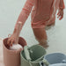 Child in striped swimsuit playing with buckets in water
