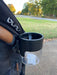 Black cup holder attached to a stroller with a park background
