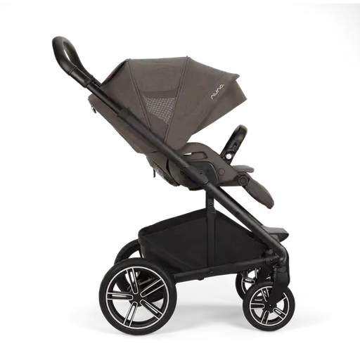 A side profile view of a Nuna stroller in dark grey and black, featuring a large canopy, padded seat, and four wheels with a stylish black and silver rim design, set against a plain white background.