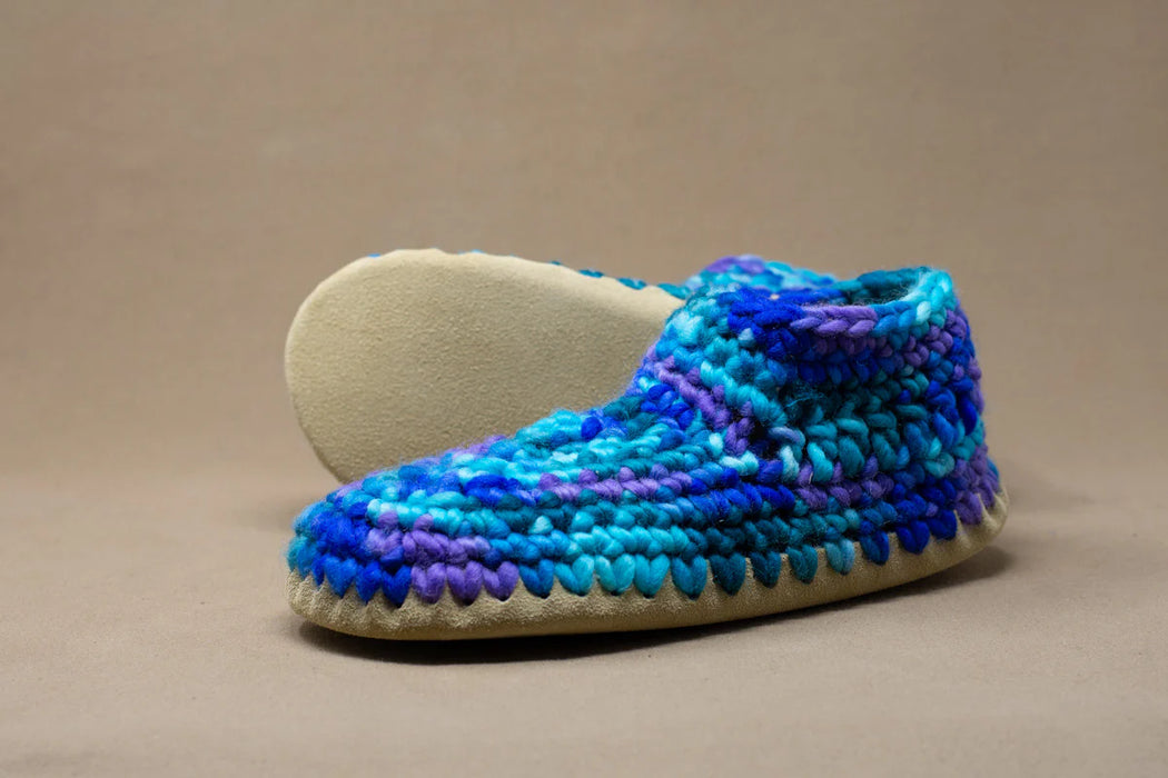 Blue and purple crocheted slipper on a beige background