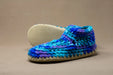 Blue and purple crocheted slipper on a beige background