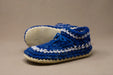 Blue and white crocheted slippers on a beige background