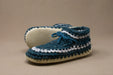 Pair of blue and white crocheted slippers on a beige background